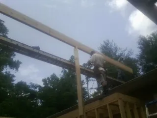 Carpenter setting a ridge beam over a new addition frame — Ice Dam Removal by Roofing Brothers in Moundville