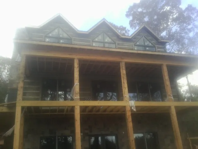 Dormers and porch framing on a large log home under construction — Roof Coating work by our crew in Moundville