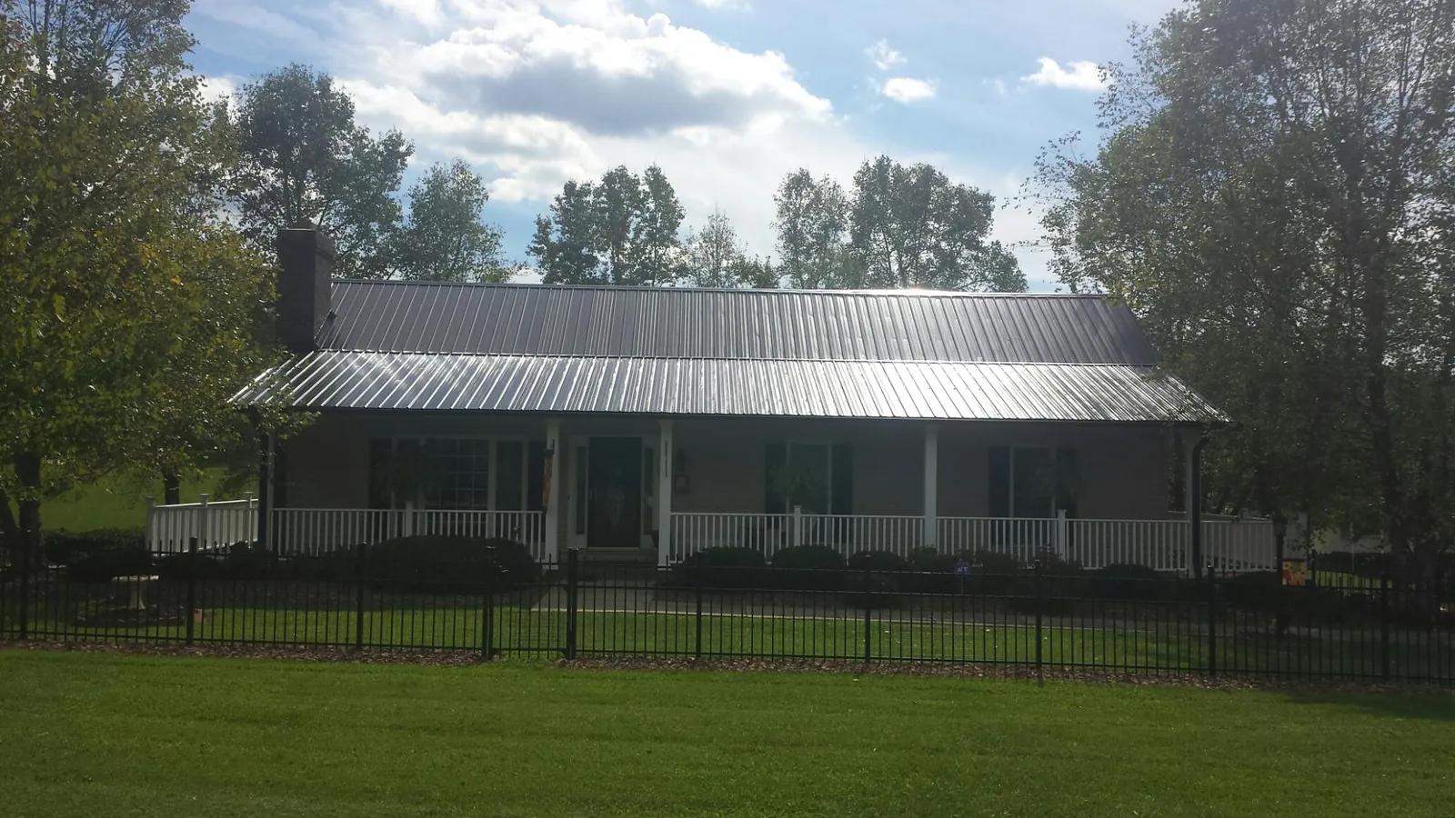 Gray metal roof on a brick ranch with a full width front porch — Gutter Guard Installation work by our crew in Moundville