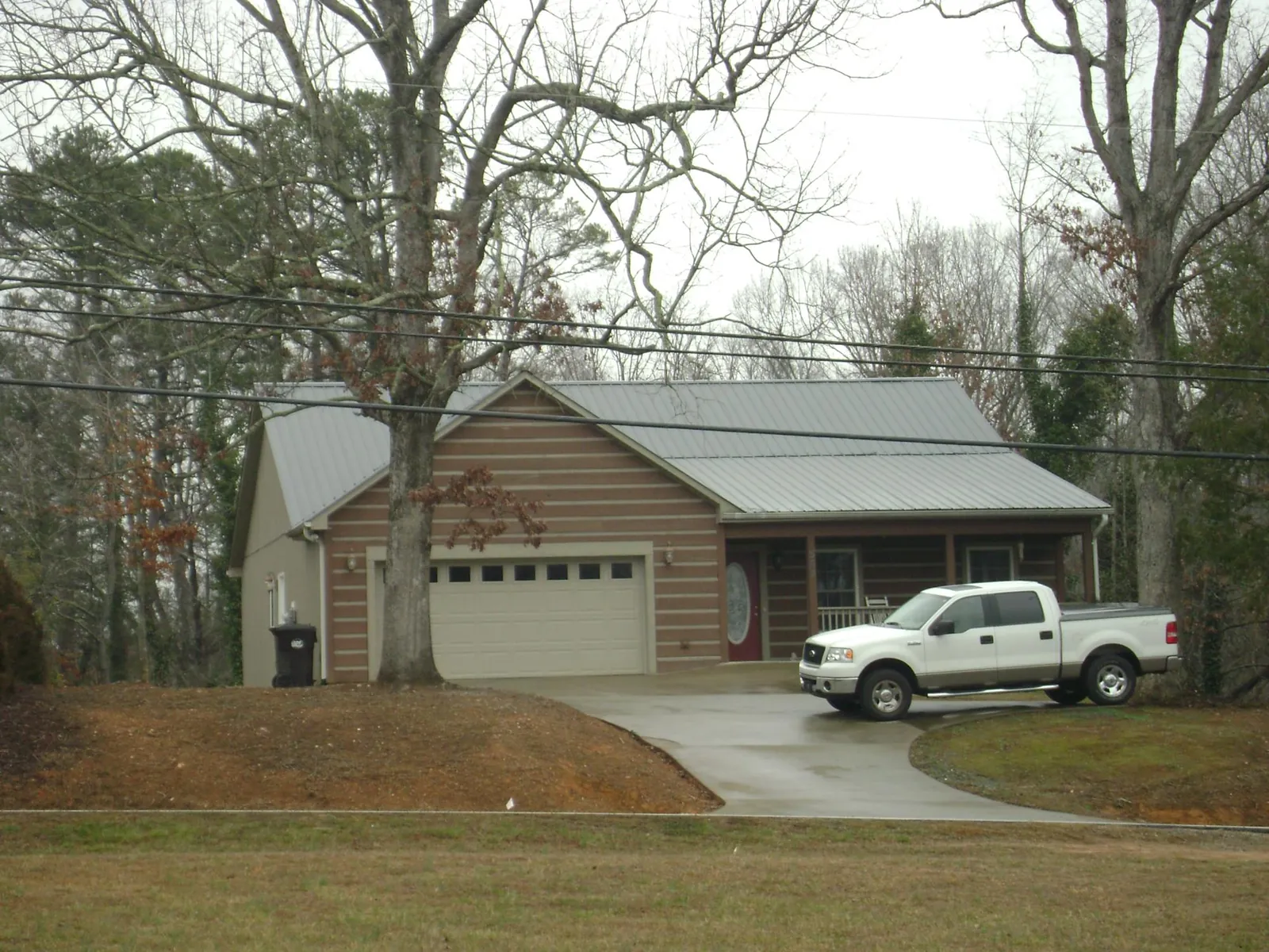 Gray metal roof on a log sided house with an attached two car garage in Moundville