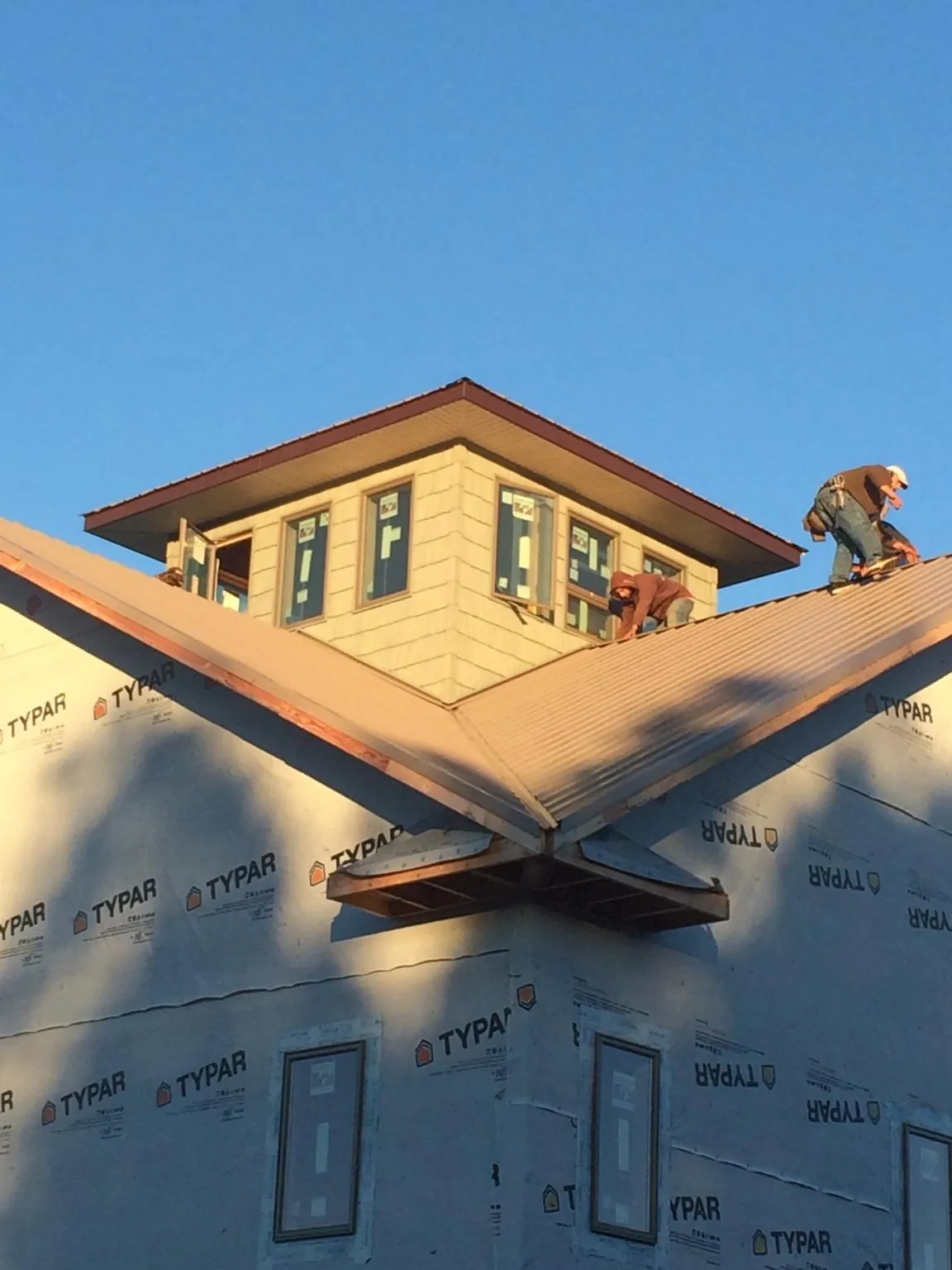 Roofers working around a rooftop cupola on a new metal roof at sunset — Roof Waterproofing in Moundville by Roofing Brothers